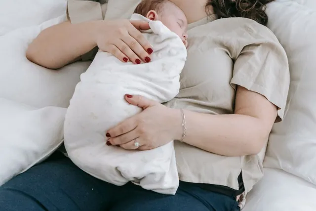 A mother resting with her swaddled newborn