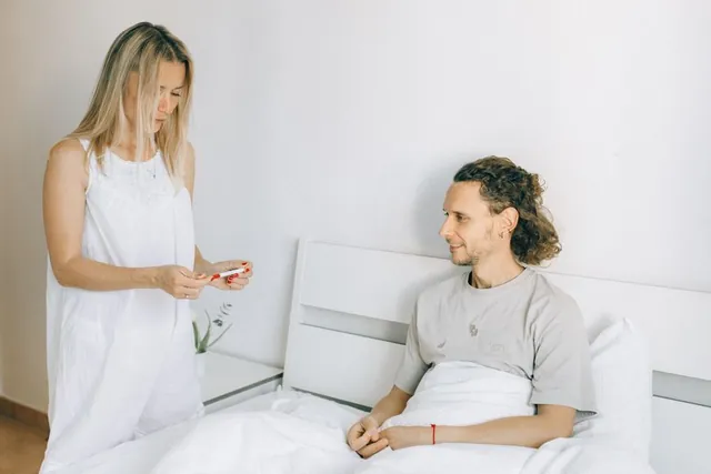 A couple in a bright bedroom with a pregnancy test
